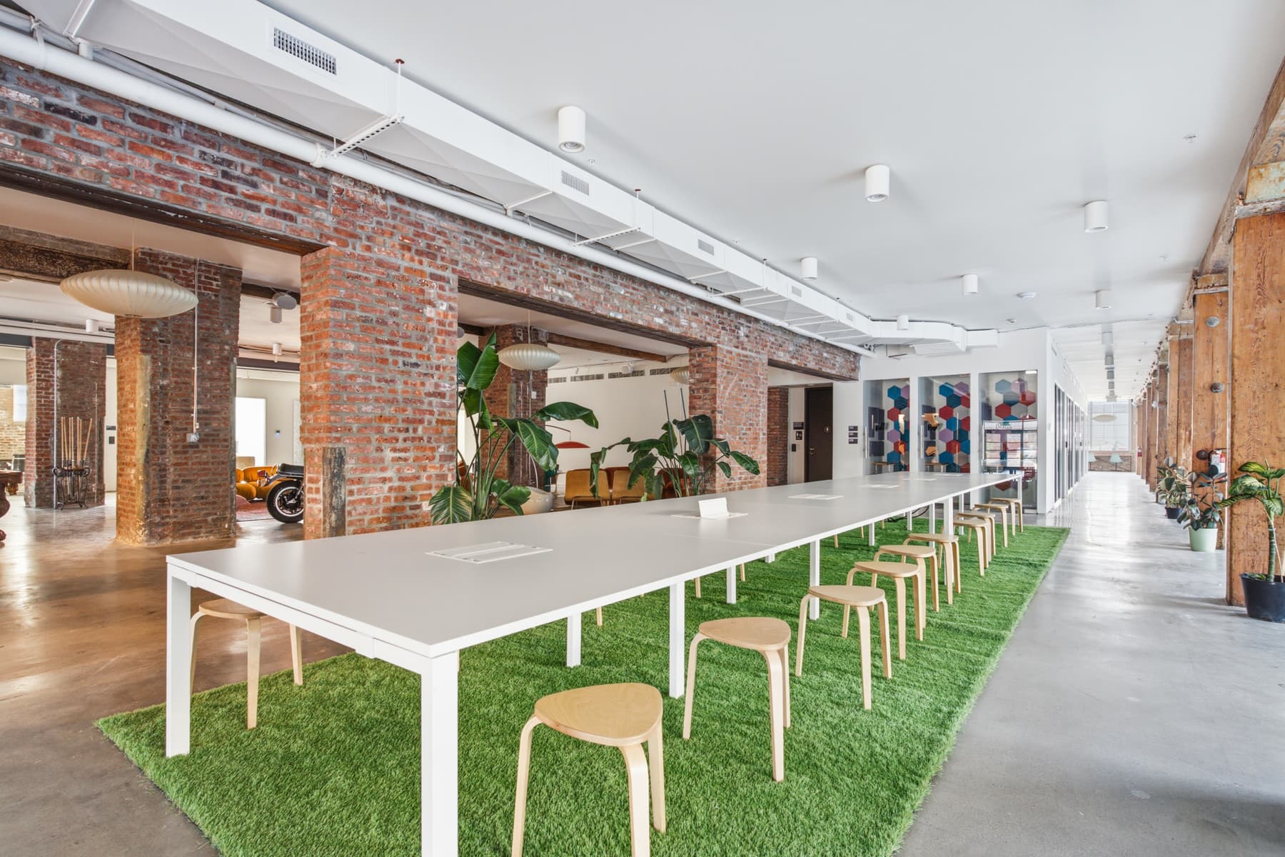 Open coworking with long communal tables, power at every seat, and exposed brick Open coworking with long communal tables, power at every seat, and exposed brick