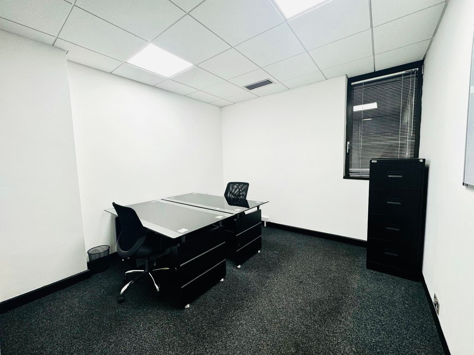 2 person spacious furnished office with window, desks and office chairs.