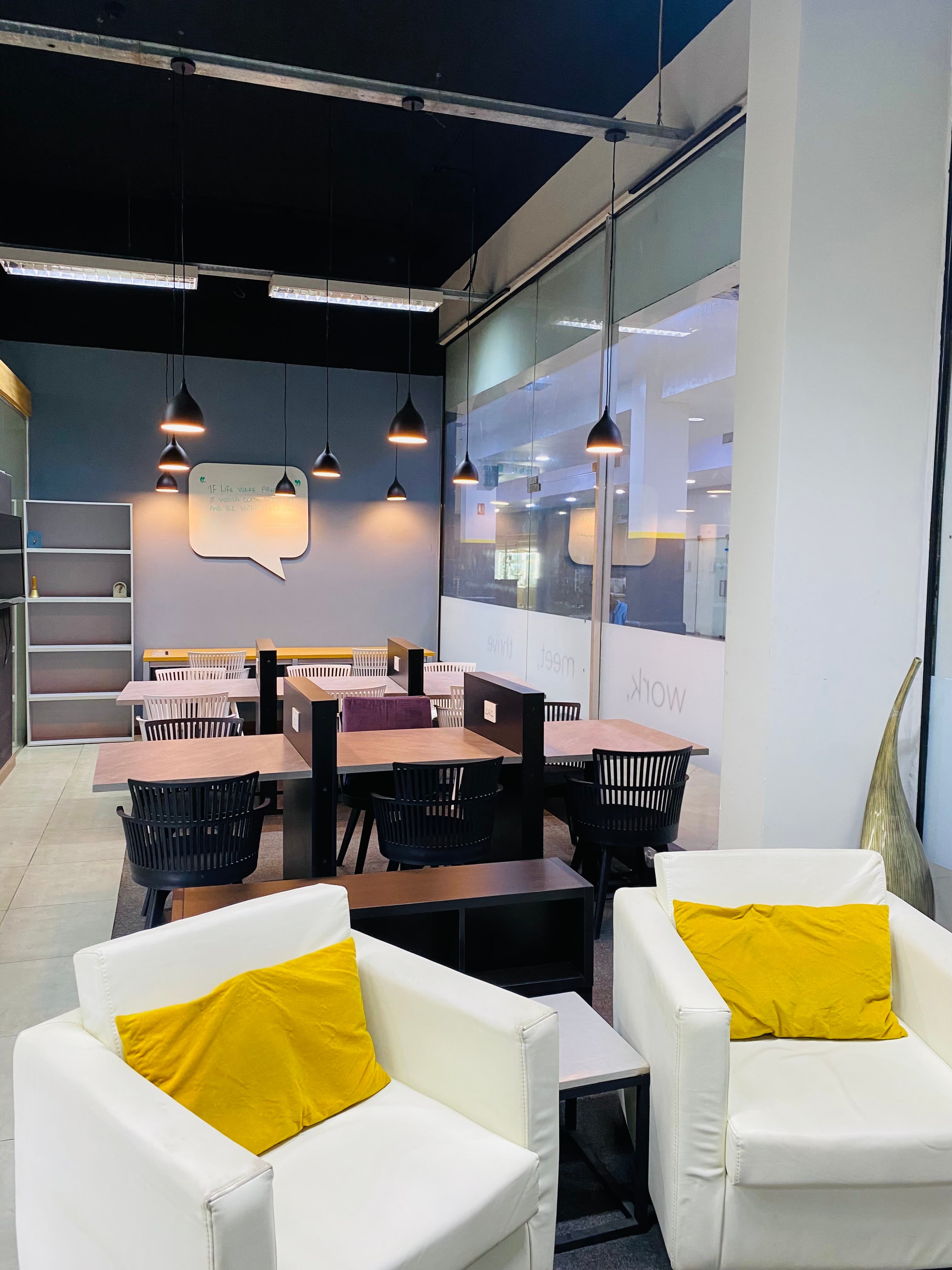 A bright and well-arranged open workspace with shared desks, comfortable chairs, good lighting, and a quiet atmosphere that