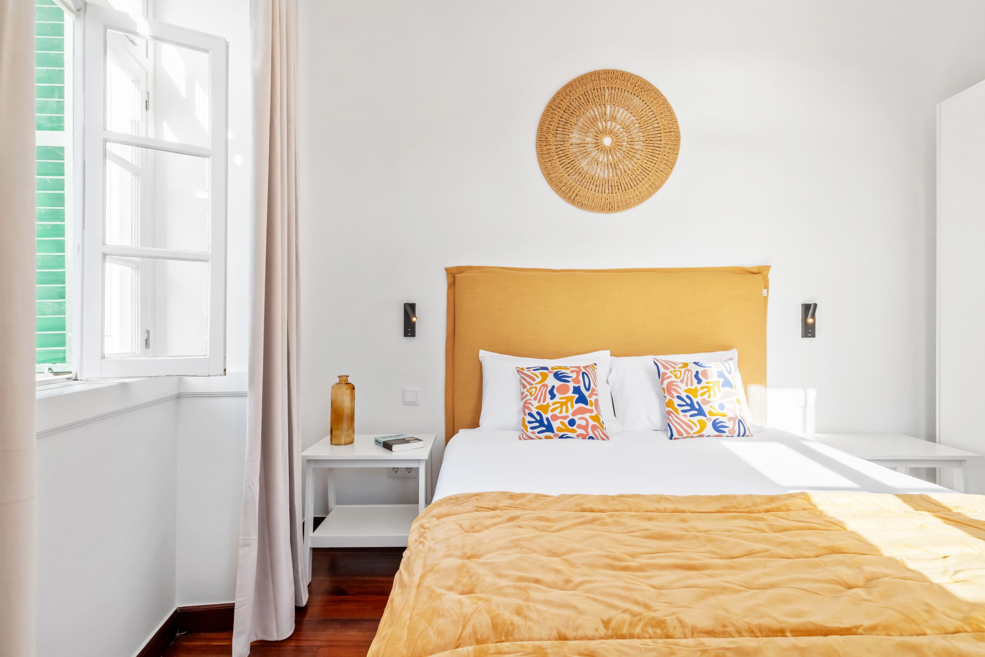 Comfortable private bedroom featuring a cozy bed with a yellow headboard, vibrant decor, and bright natural light.