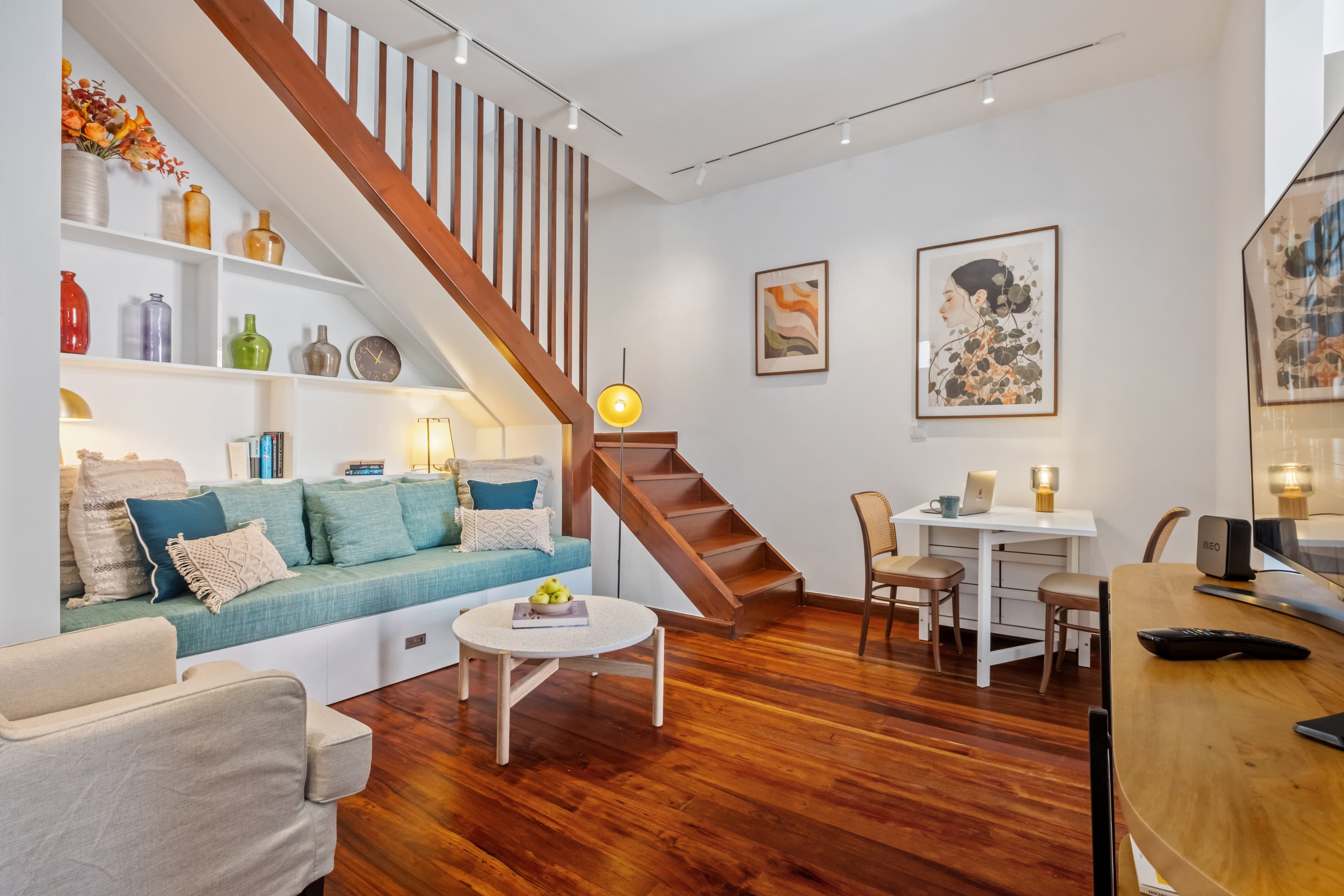 Cozy split-level lounge area with comfortable seating, a dedicated work desk, and a wooden staircase.