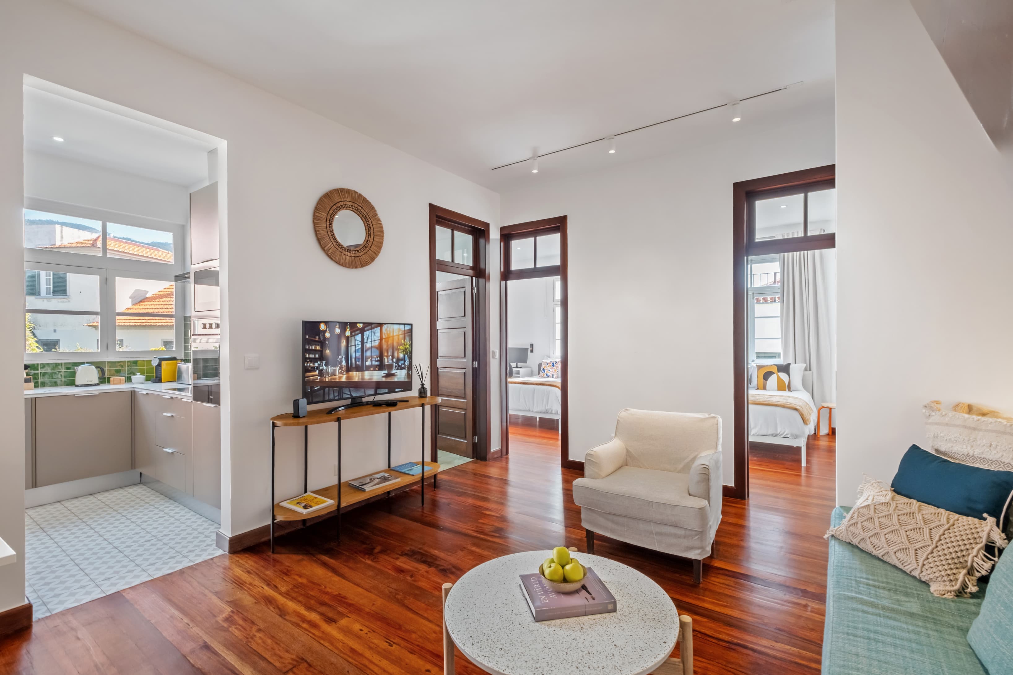 Spacious shared living area with a flat-screen TV, comfortable seating, and beautiful hardwood floors connecting the rooms.