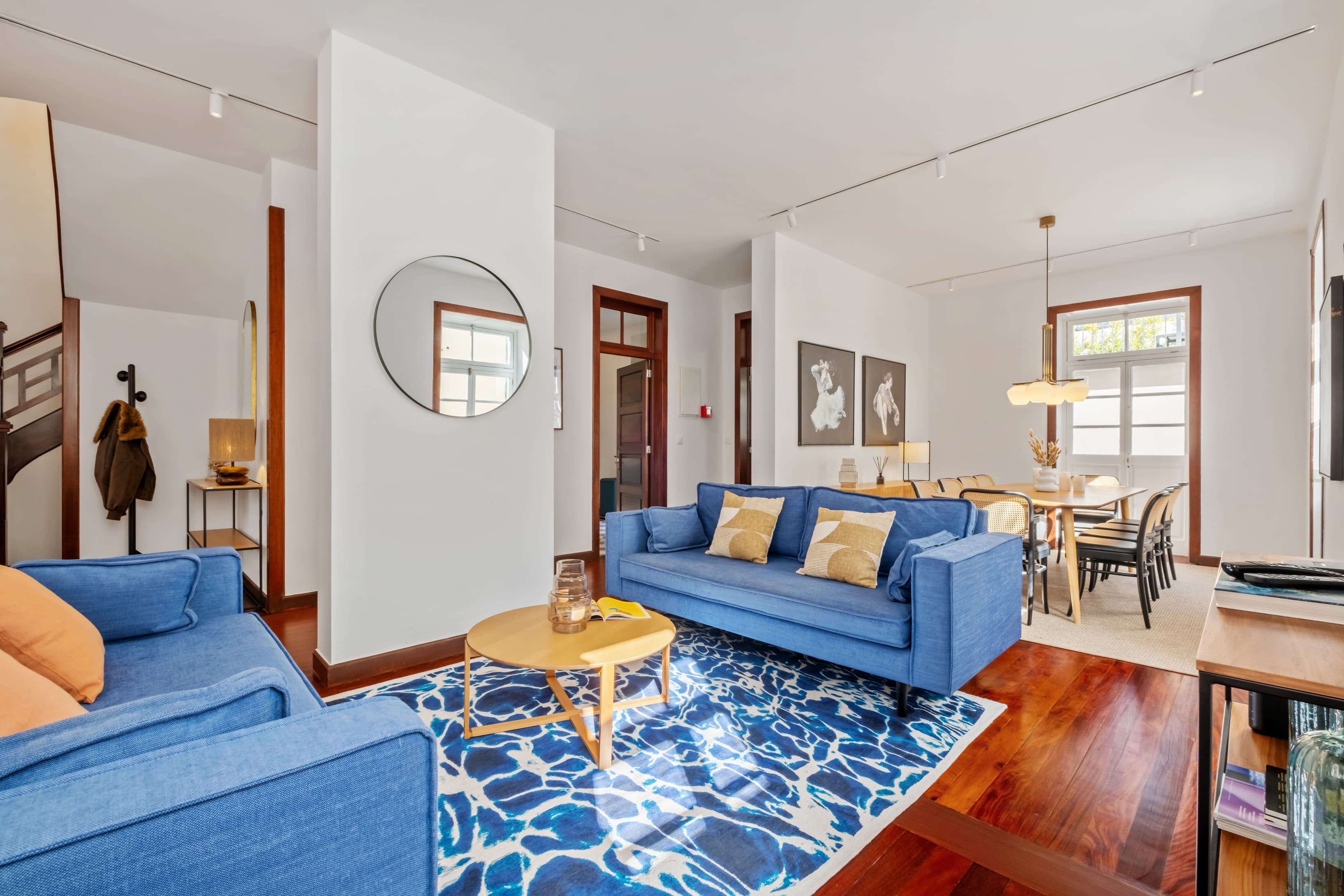 Inviting living room featuring a vibrant blue sofa, matching patterned rug, and warm wooden floors.