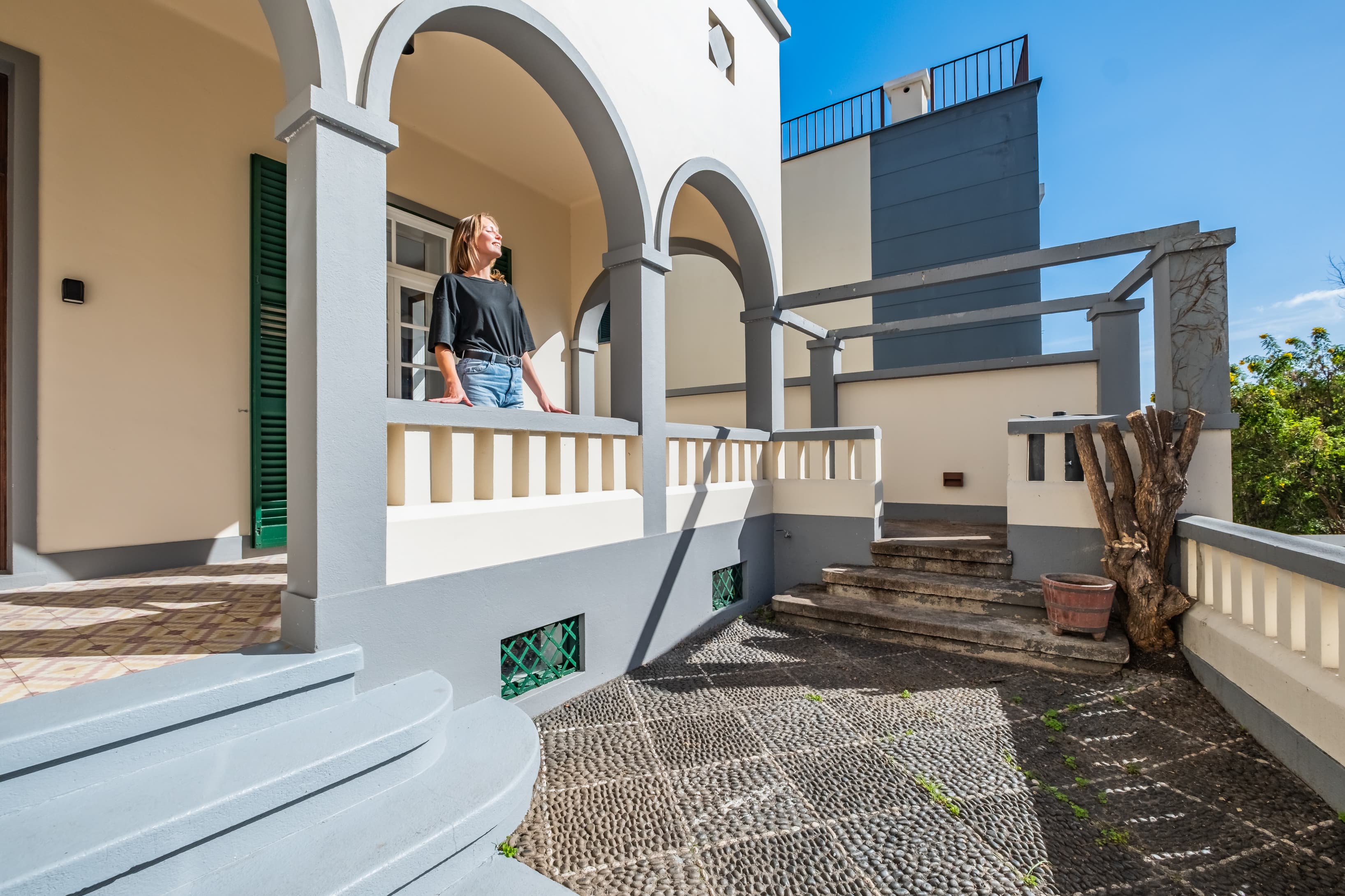 Traditional exterior architecture featuring cobblestone details, shaded arches, and a spacious balcony area.