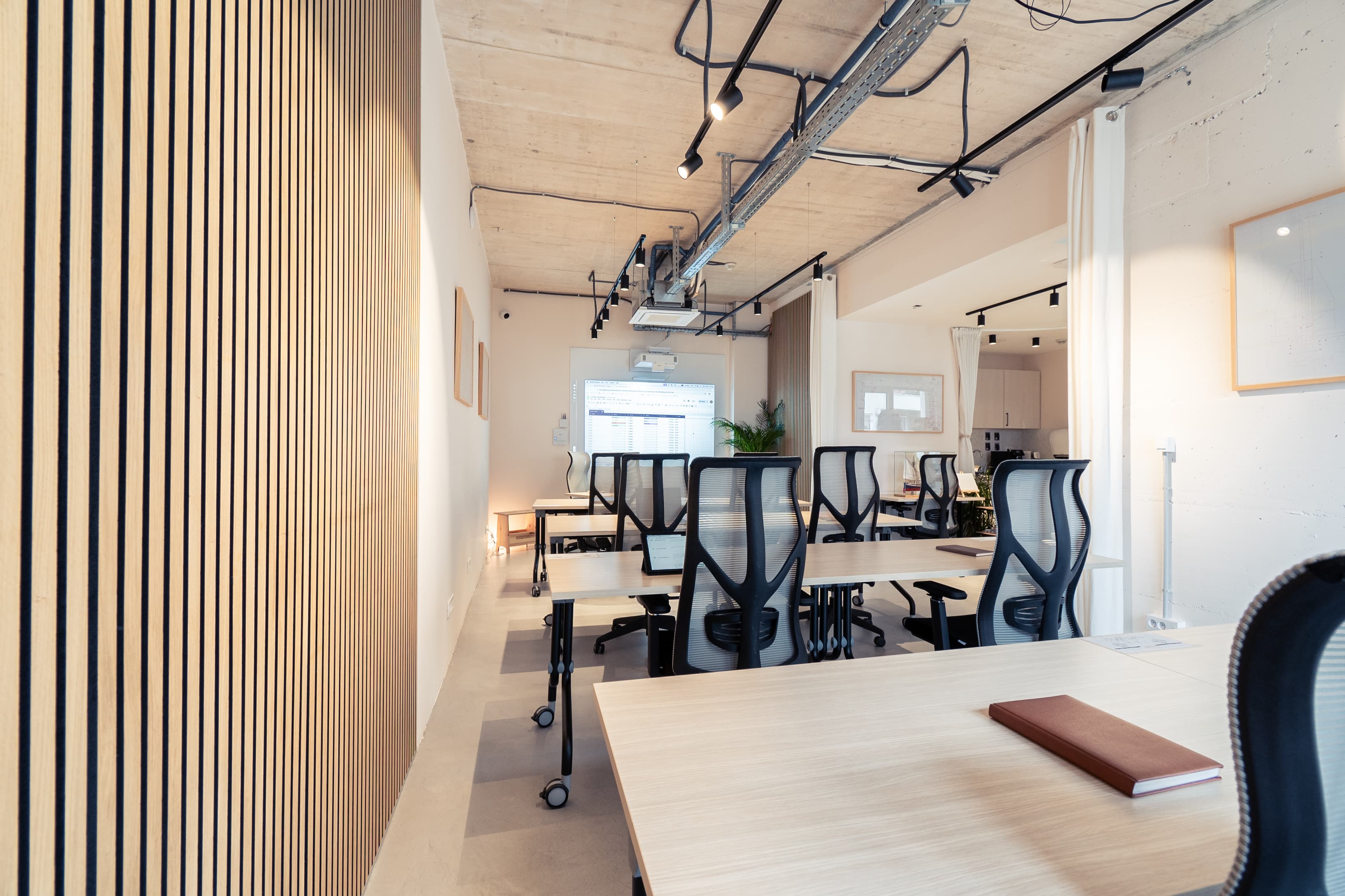Open workspace filled with natural light, greenery, and modern chairs — easily rearranged for classroom or workshop setups.
