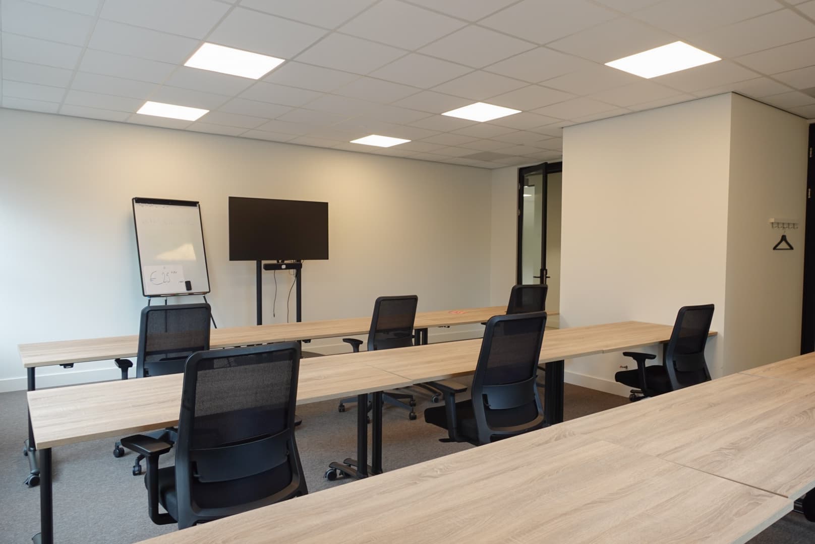 Spacious meeting room with classroom-style seating, a presentation screen and a flipchart, ideal for training sessions