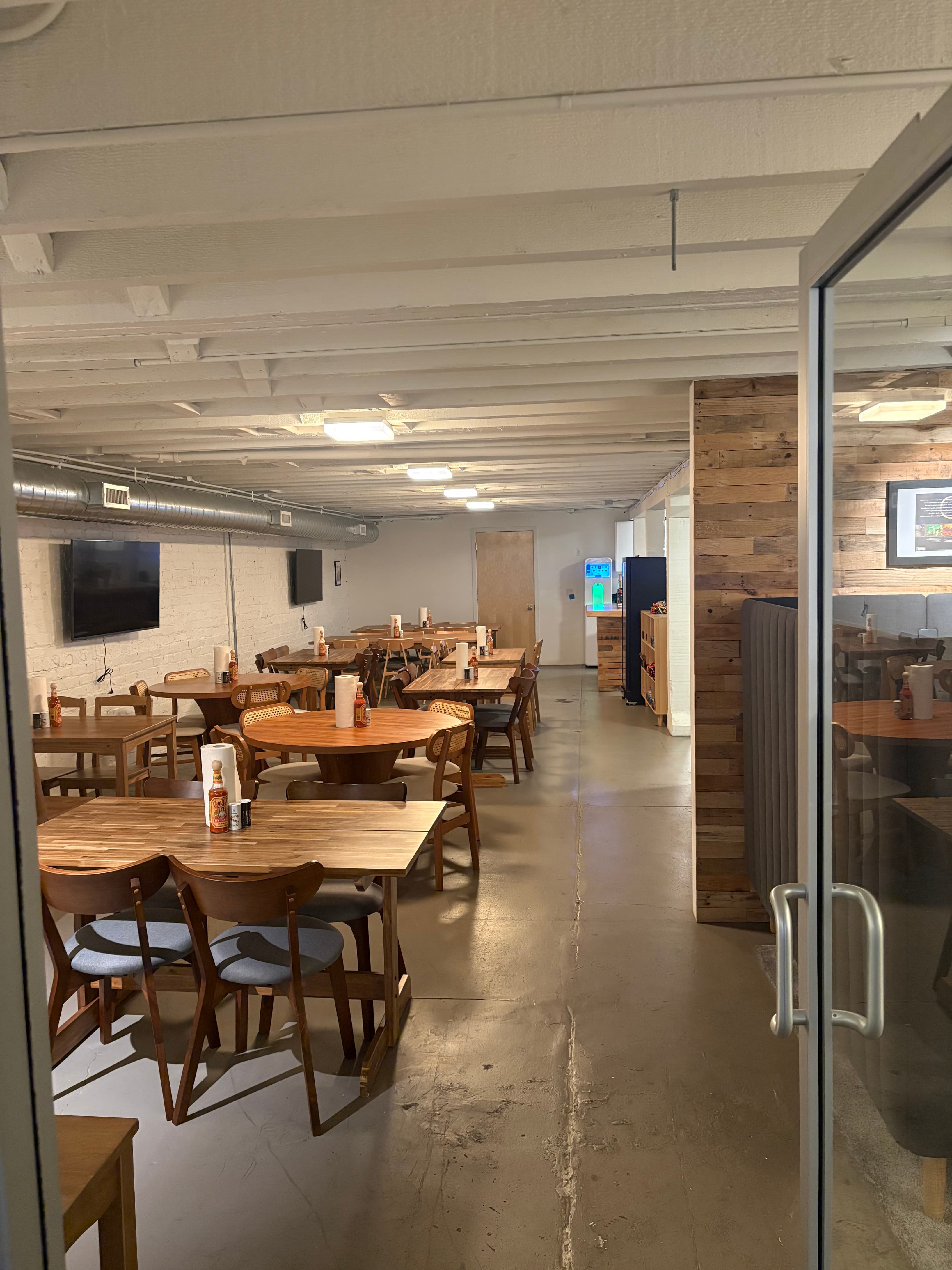 Spacious dining area with multiple wooden tables and comfortable seating perfect for team lunches, casual meetups, and commun