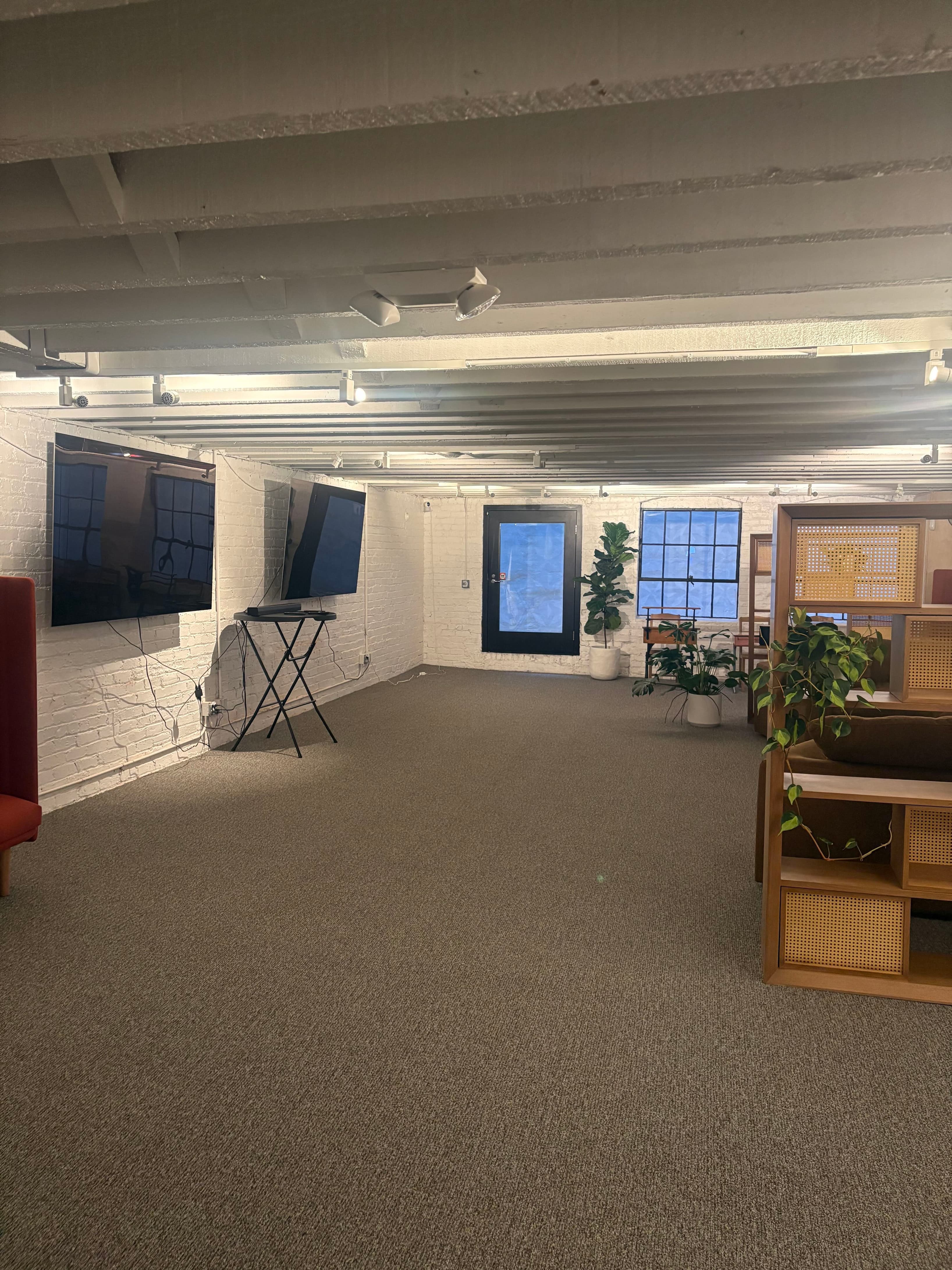Flexible room with dual display screens and open layout for presentations, demos, or events. Modern audio-visual setup ready 