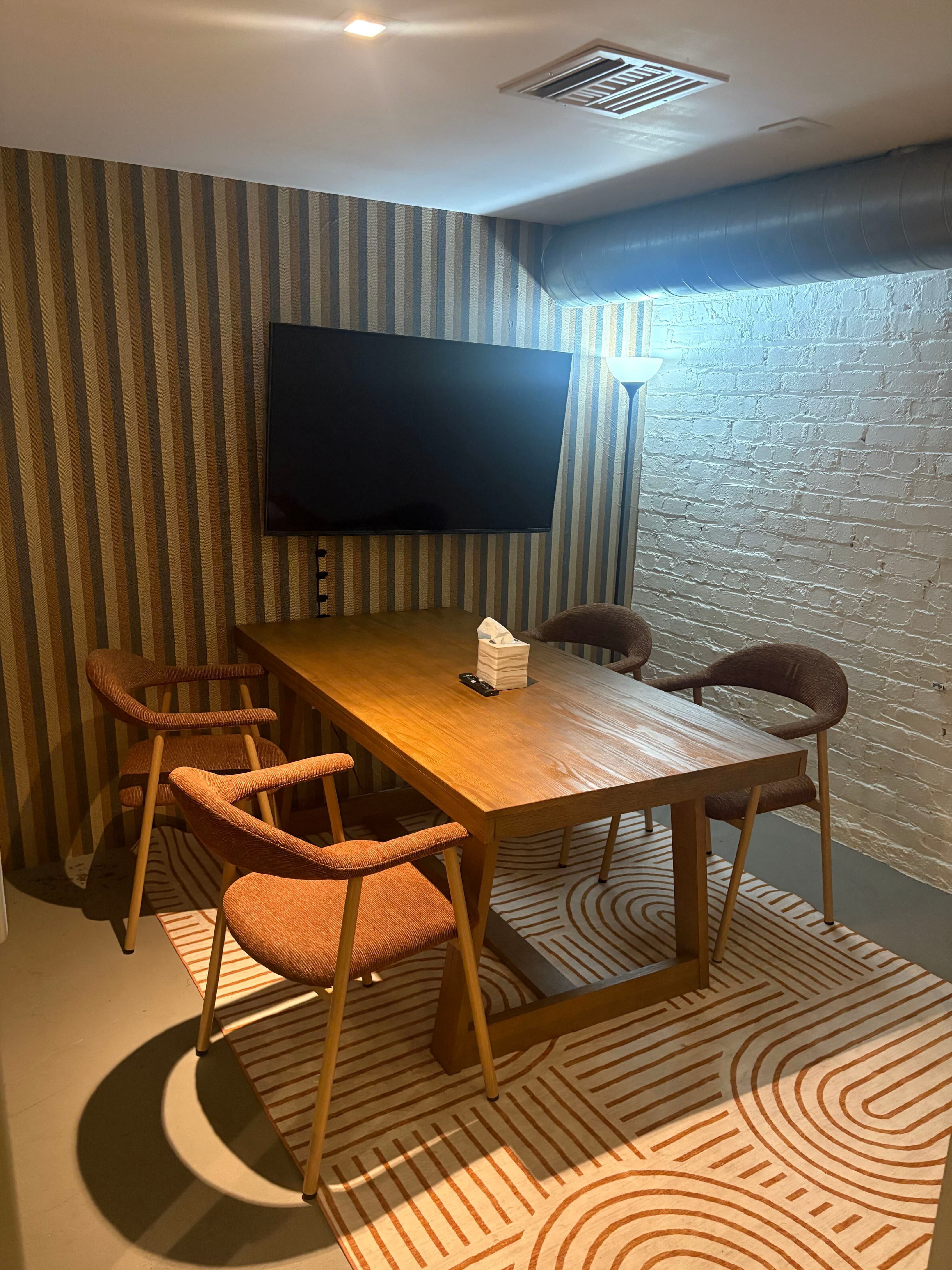 Intimate conference room designed for focused one-on-ones or small team meetings. Mid-century modern furnishings, display mon
