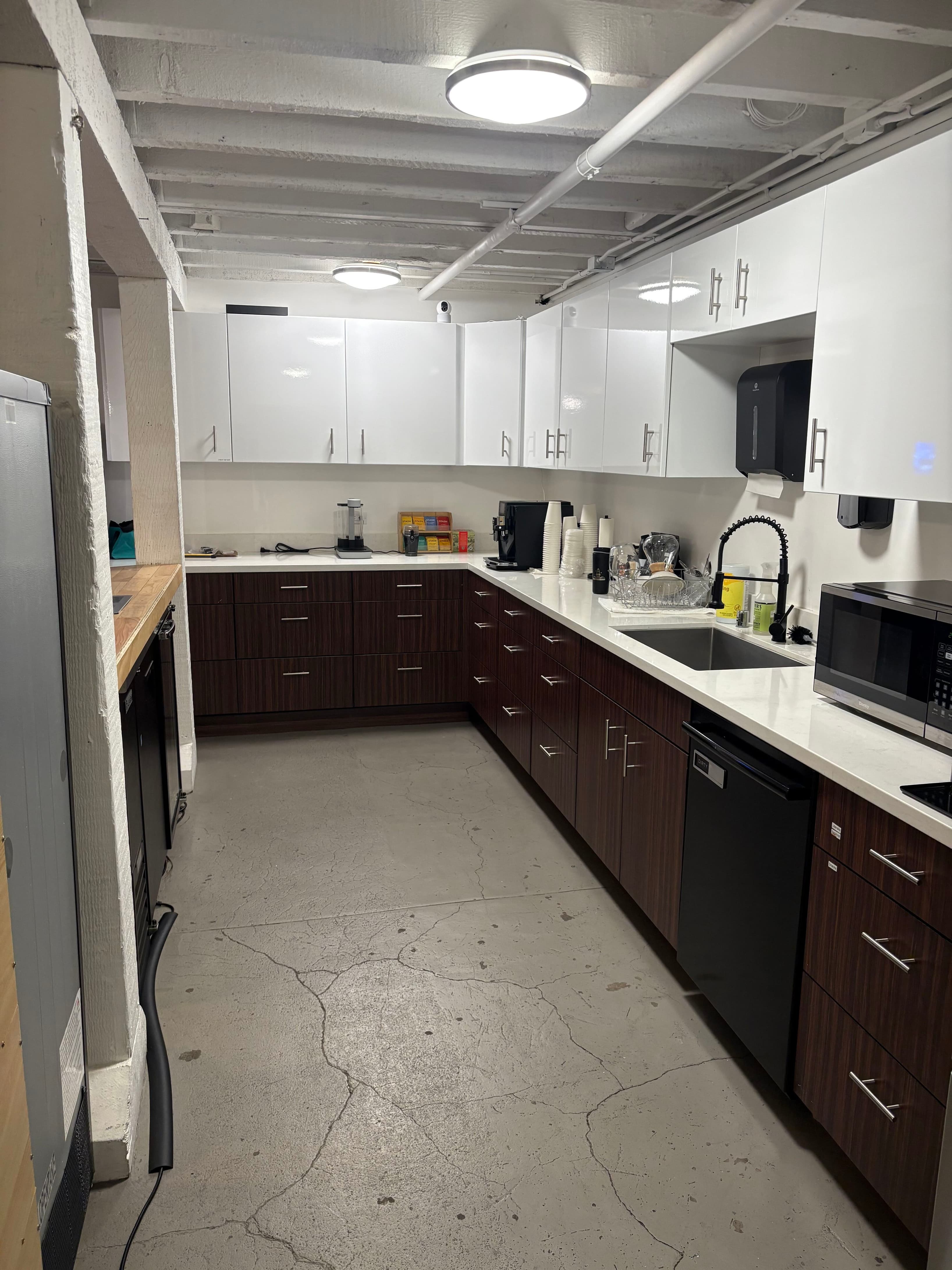 Full-service kitchen stocked with modern appliances including refrigerator, dishwasher, and microwave. Clean white countertop