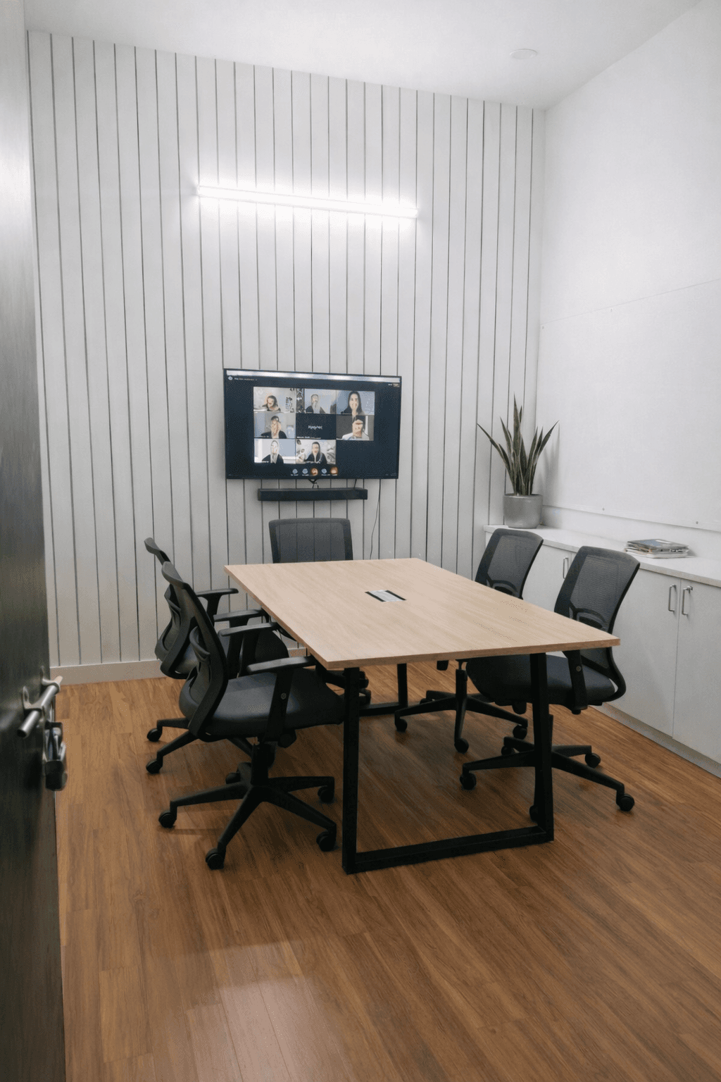A professional coworking area featuring sleek wooden desks and ergonomic black mesh chairs. The space is finished with high-q