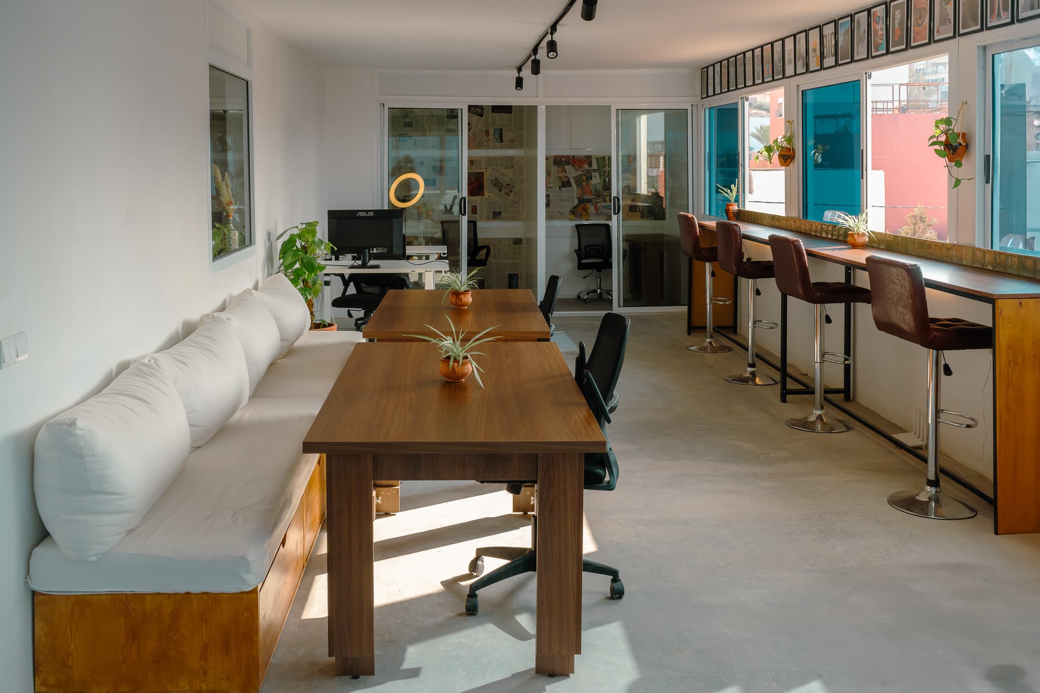 Main coworking area at Amsiln Studio with wooden desks, ergonomic chairs, sofa, natural light, and sea views in Tamraght.