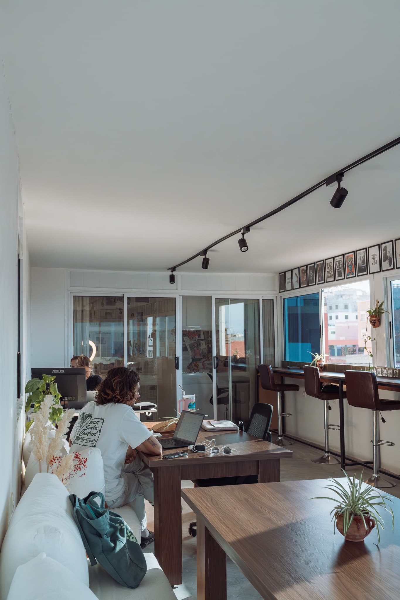 Full view of Amsiln Studio with desks, high stools, cozy seating, and phone booths in a bright space with sea views.