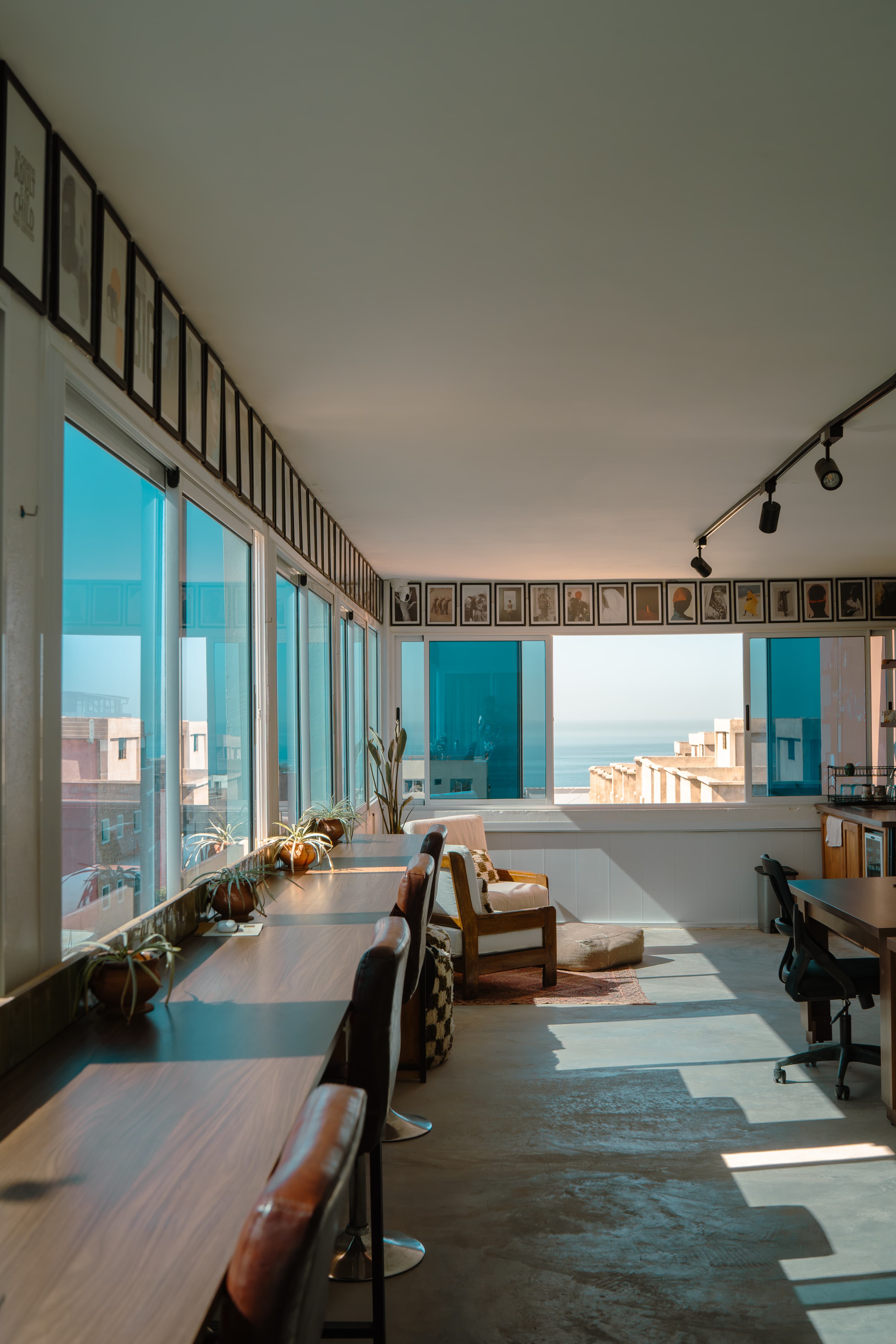 High desk workspace with natural light and floor-to-ceiling windows over the Atlantic and Tamraght rooftops, top work view.