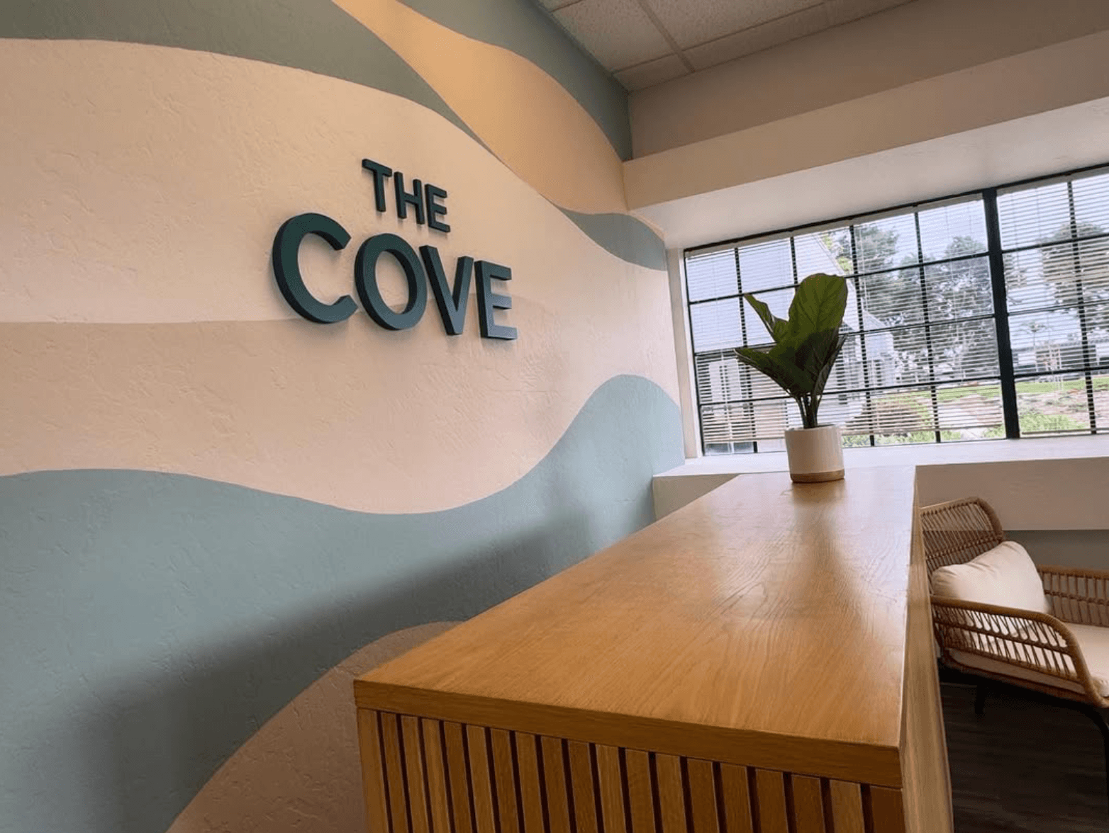A welcoming view of The Cove reception area, featuring our signature wave mural, natural wood finishes, and calm design.