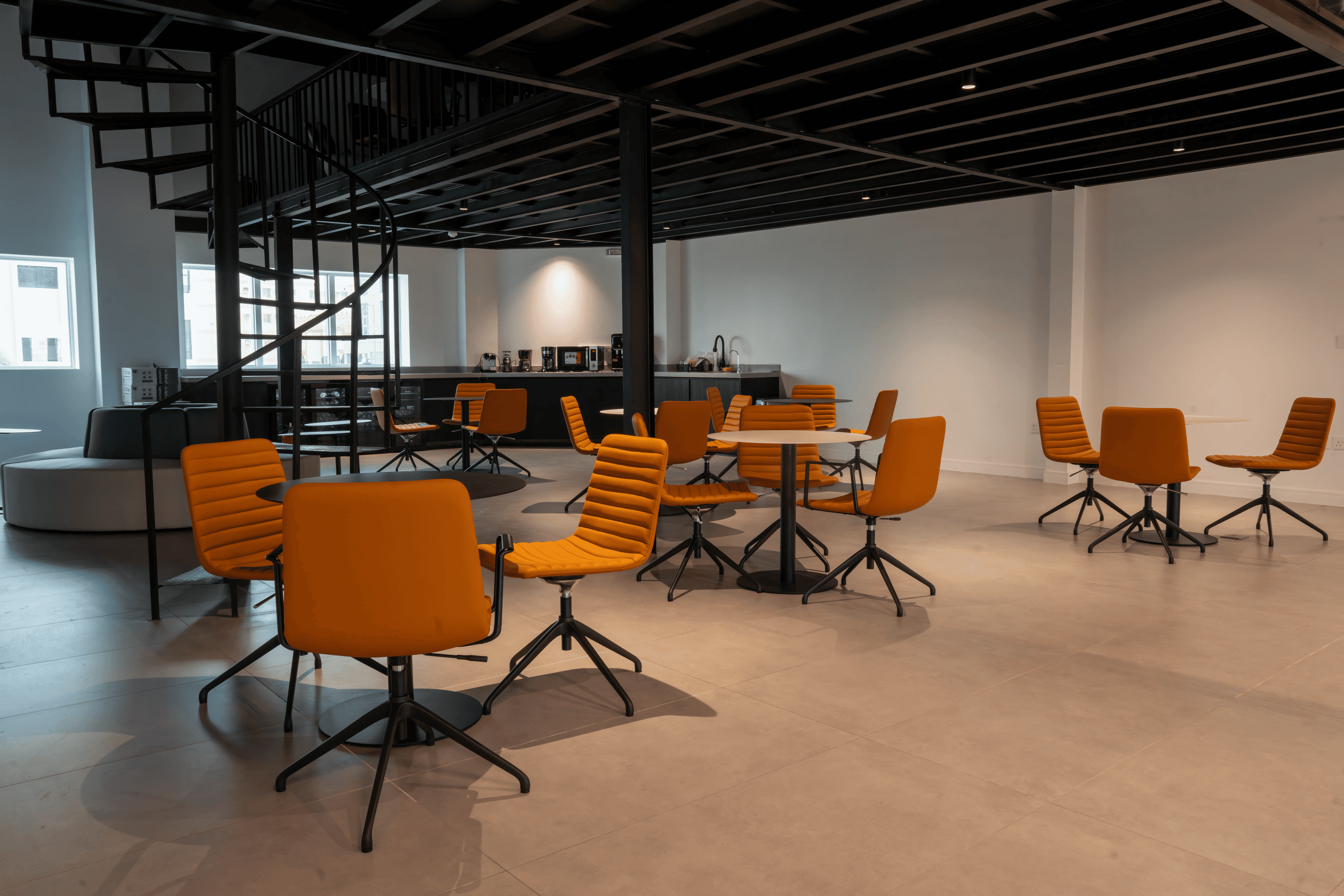 Dining or Break Area: A view of a stylish dining or break area with several orange chairs around a sleek table, set in a cont Dining or Break Area: A view of a stylish dining or break area with several orange chairs around a sleek table, set in a cont