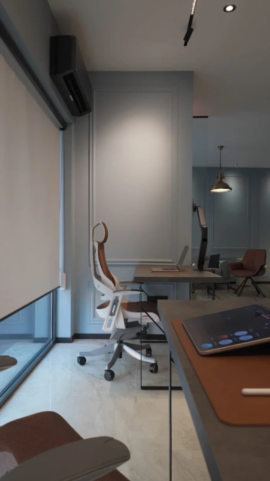 Open coworking area with multiple desks and chairs next to large windows
