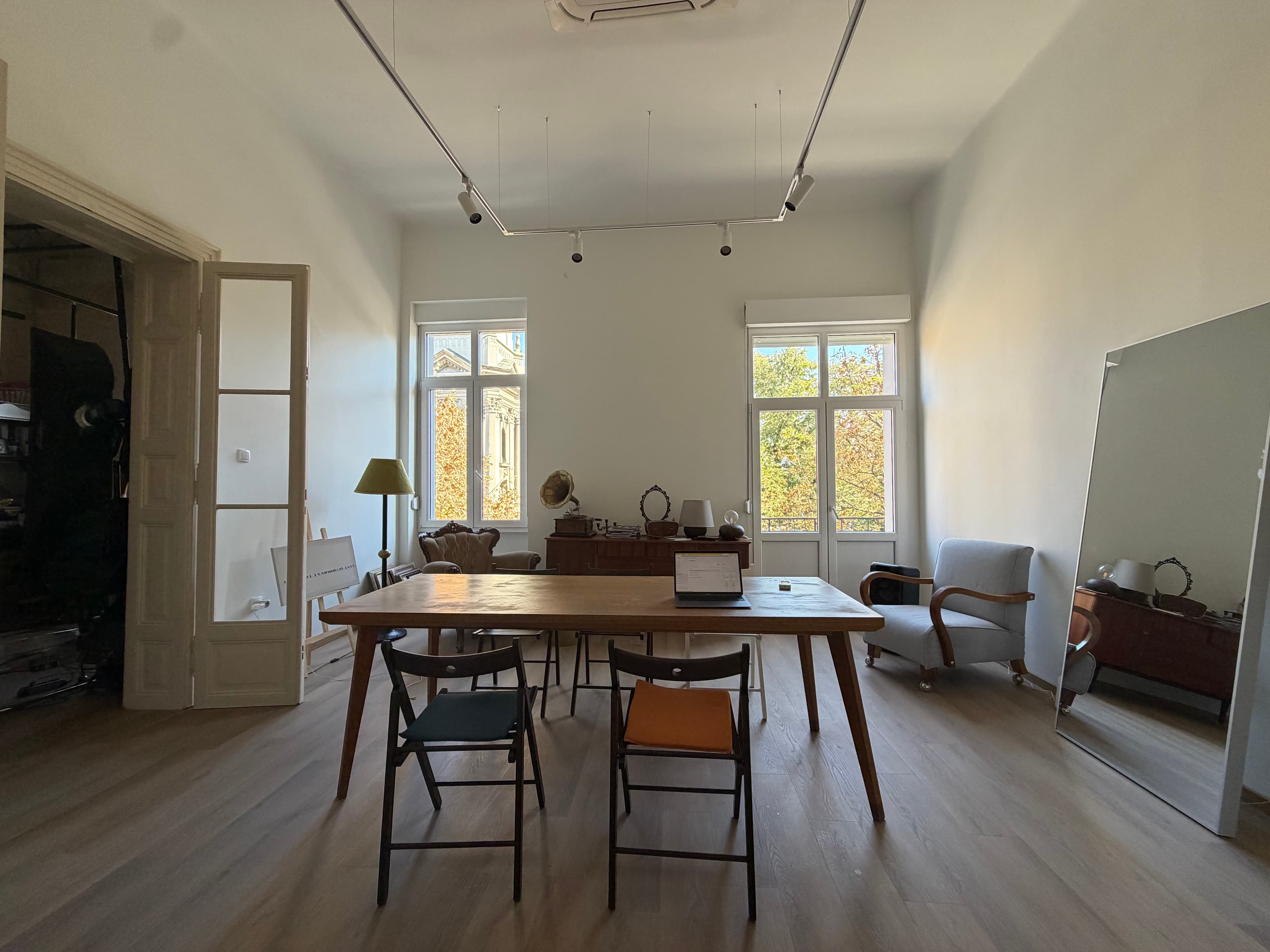 The Big Room (Event & Workshop Space) A bright, high-ceilinged room with tall windows overlooking the treetops, a large woode