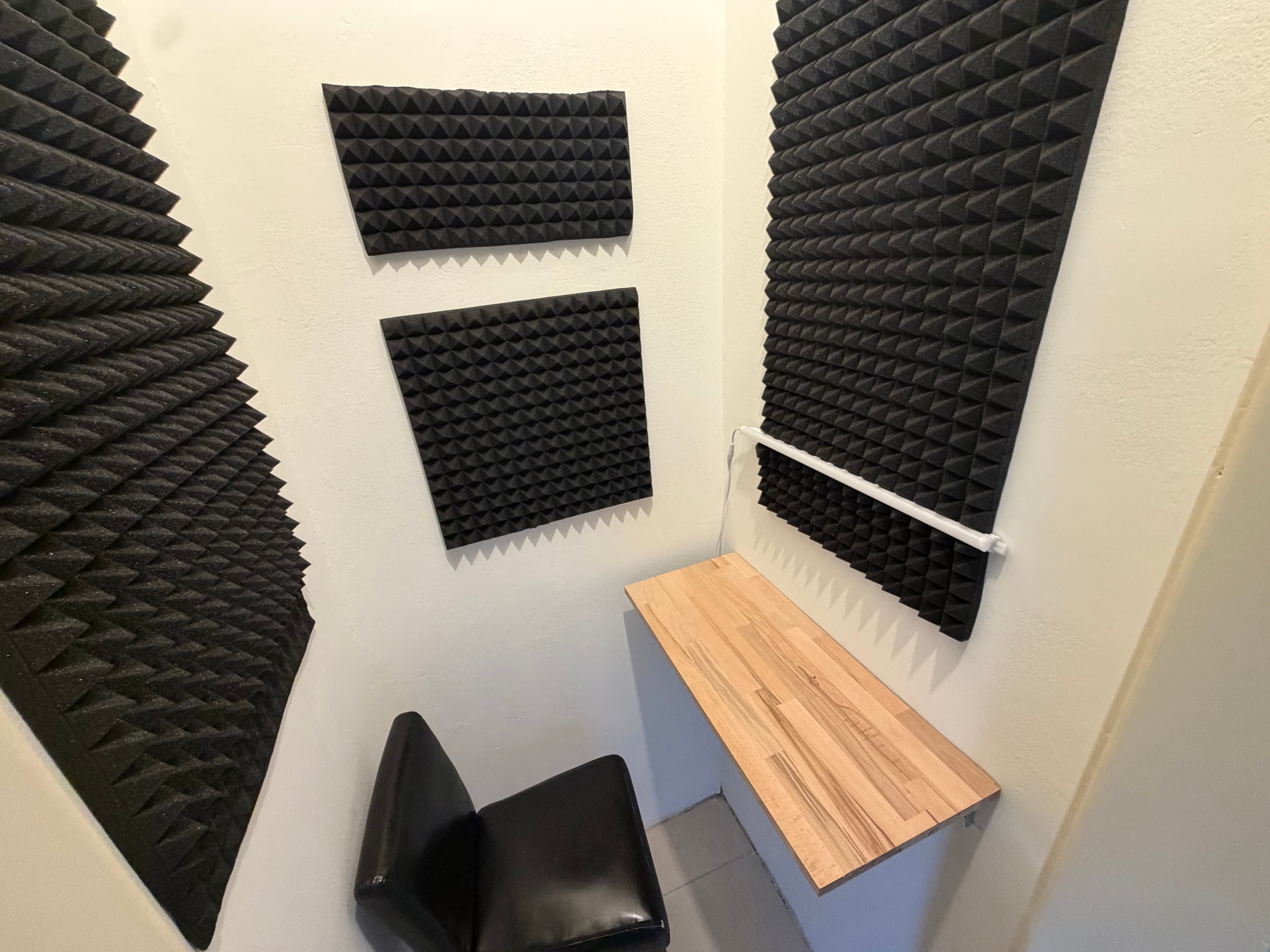 Call & Podcast Booth A small soundproofed booth with acoustic panels, a wooden desk, and a light strip.