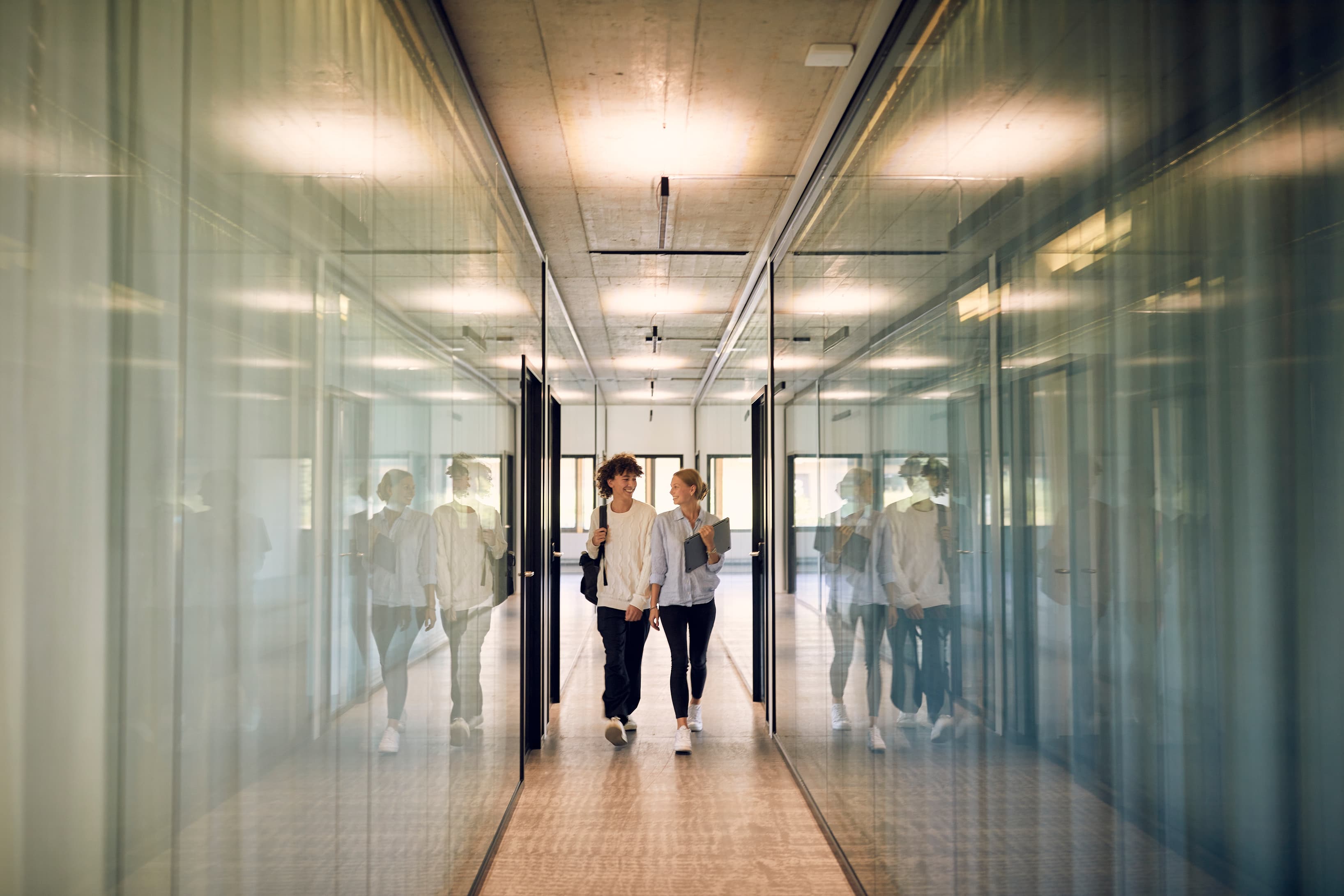 People walking through a modern, light-filled hallway at ORBIZ Noerd, surrounded by industrial design and creative energy. People walking through a modern, light-filled hallway at ORBIZ Noerd, surrounded by industrial design and creative energy.