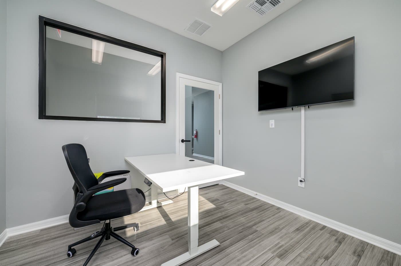 Private office with desk, wall TV and interior window (representative layout). Private office with desk, wall TV and interior window (representative layout).