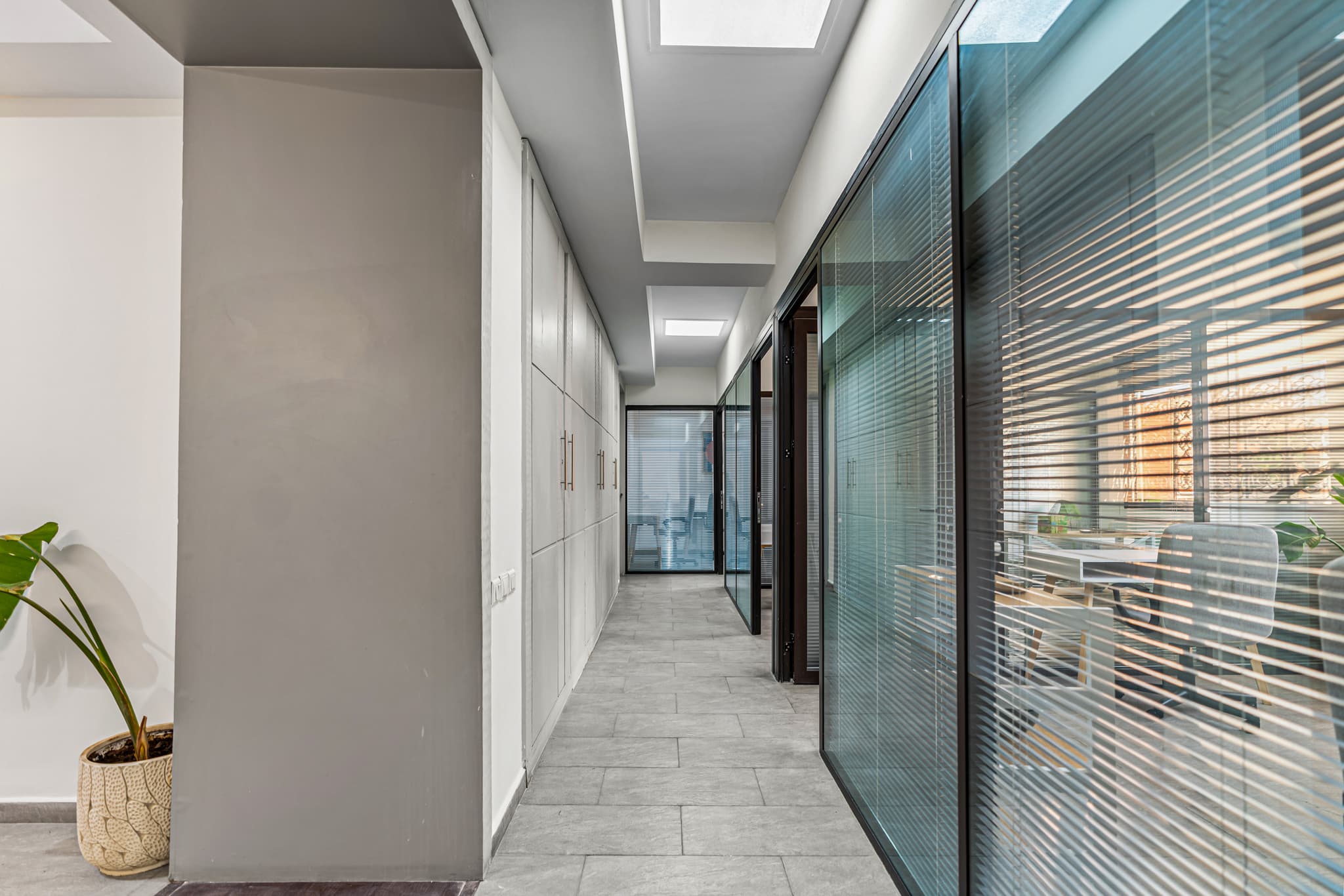 Modern office corridor at Qafila Society coworking space in Marrakech, with glass-partitioned work areas designed to provide Modern office corridor at Qafila Society coworking space in Marrakech, with glass-partitioned work areas designed to provide