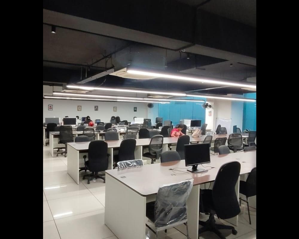 Modern coworking space in Coimbatore with spacious shared desks, ergonomic chairs, and a well-lit open office layout designed Modern coworking space in Coimbatore with spacious shared desks, ergonomic chairs, and a well-lit open office layout designed