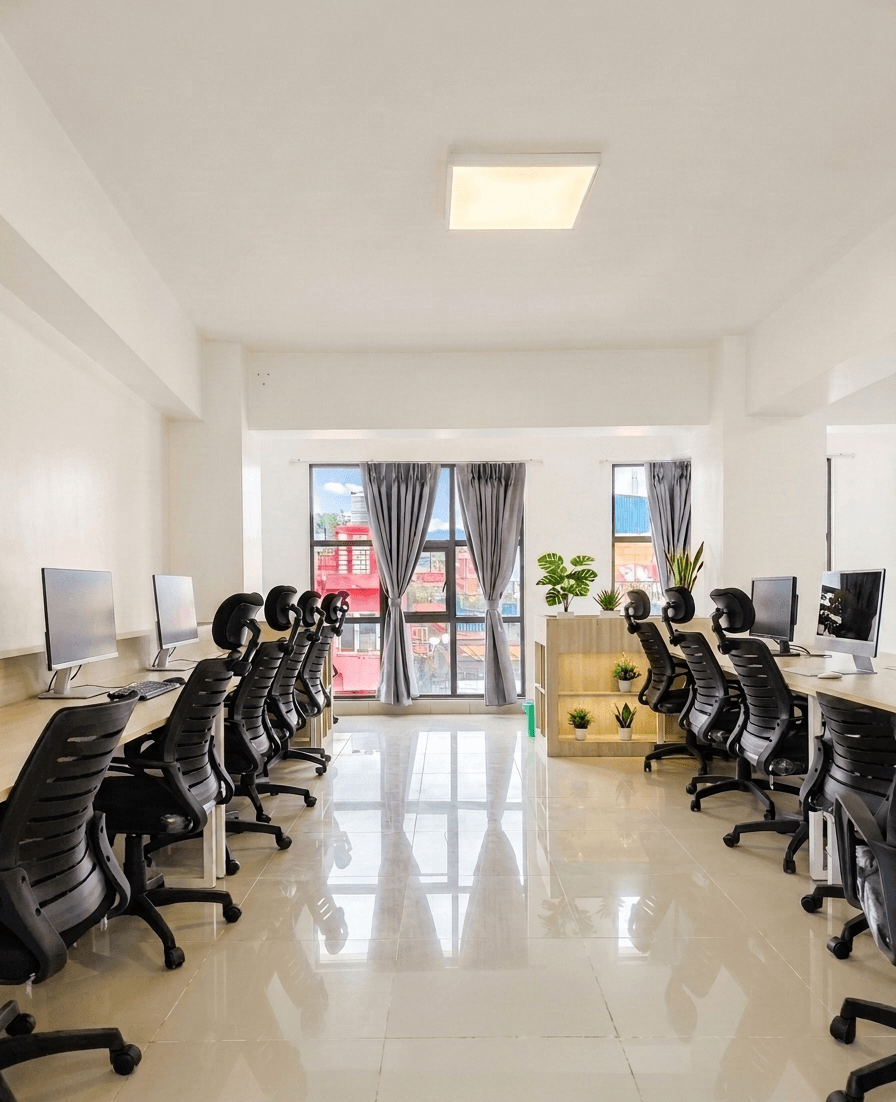 Row of ergonomic chairs and desktop setups with city view and natural light. Row of ergonomic chairs and desktop setups with city view and natural light.