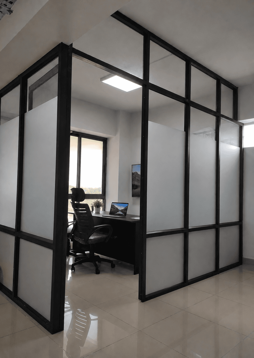 Frosted glass cabin offering privacy with a window-side desk setup. Frosted glass cabin offering privacy with a window-side desk setup.