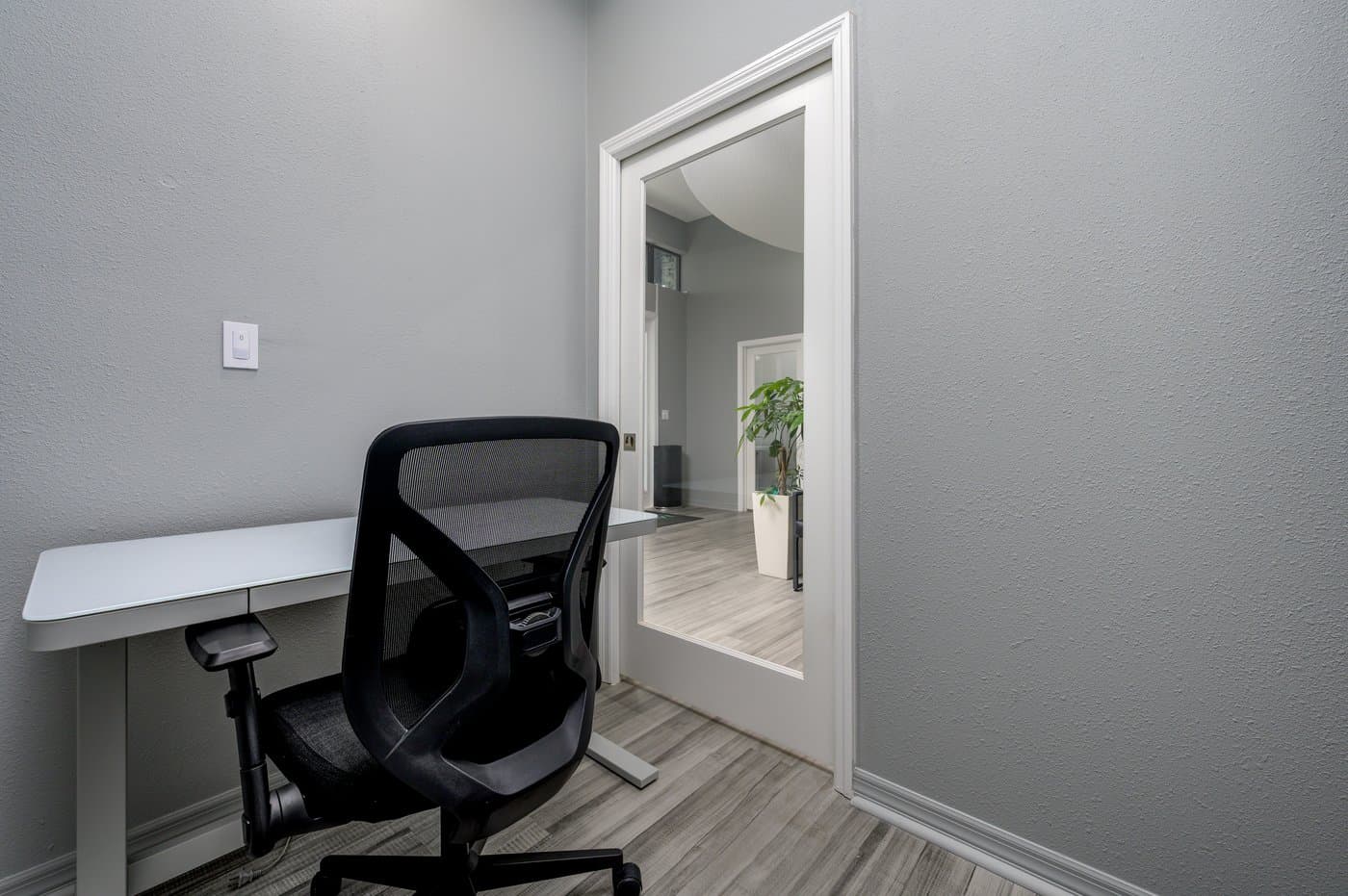 Furnished one-person office with desk and ergonomic chair (representative layout). Furnished one-person office with desk and ergonomic chair (representative layout).