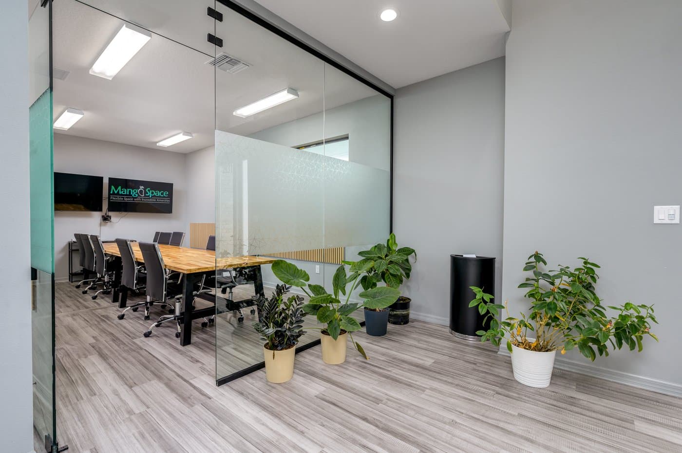 Glass-walled boardroom with a long table and wall displays for presentations and video calls. Glass-walled boardroom with a long table and wall displays for presentations and video calls.