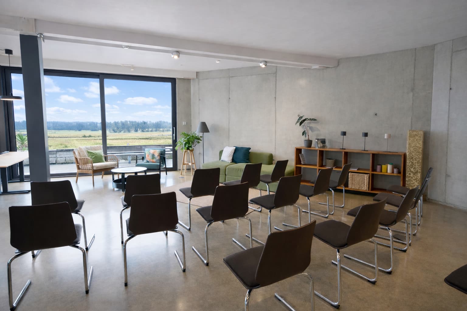 Versatile workshop room featuring row seating, a cozy lounge area, and expansive windows offering serene nature views. Versatile workshop room featuring row seating, a cozy lounge area, and expansive windows offering serene nature views.