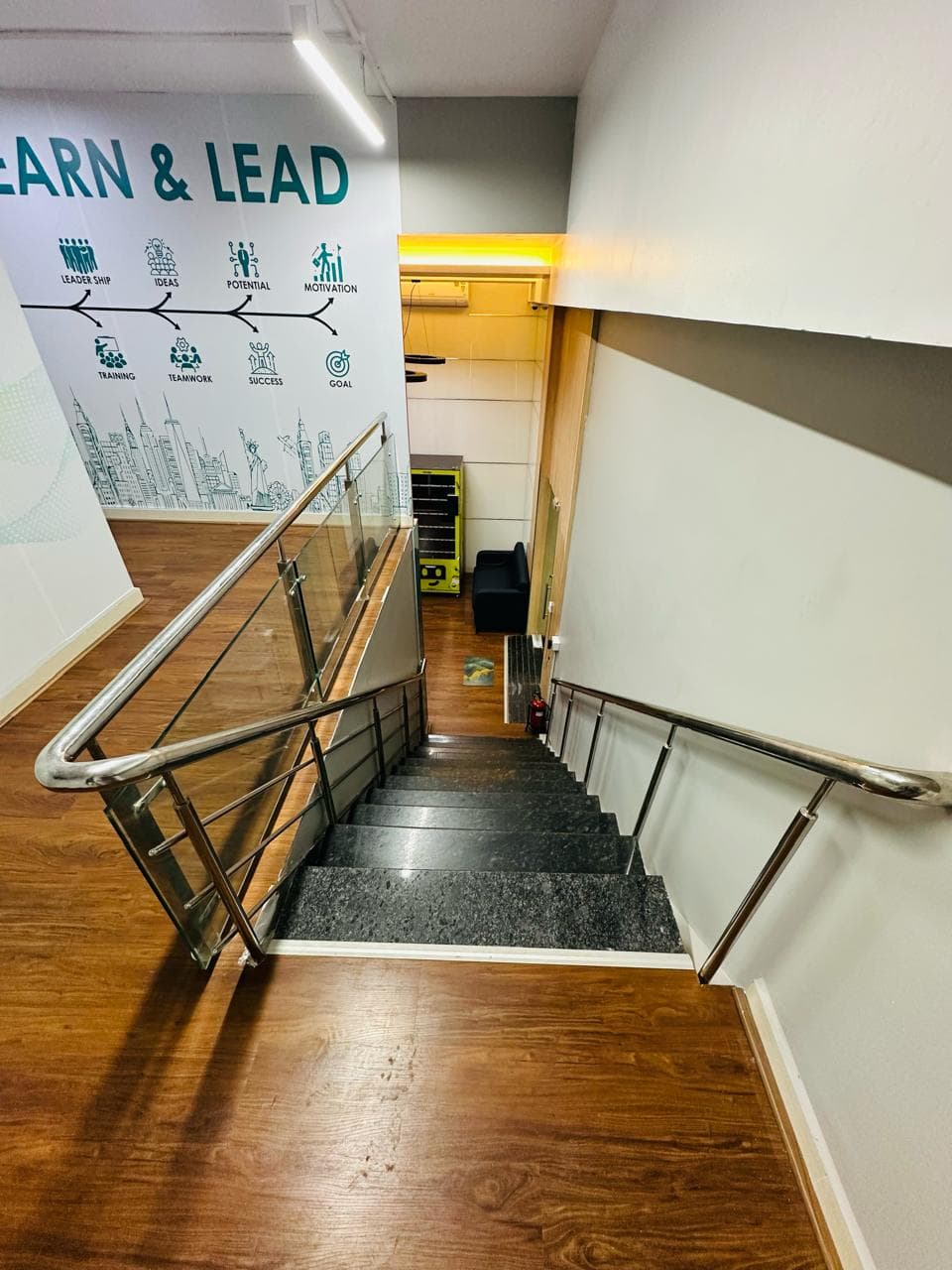 Interior staircase at Ecowrkz Guindy featuring wooden steps, glass panels and stainless steel handrails, providing convenient Interior staircase at Ecowrkz Guindy featuring wooden steps, glass panels and stainless steel handrails, providing convenient