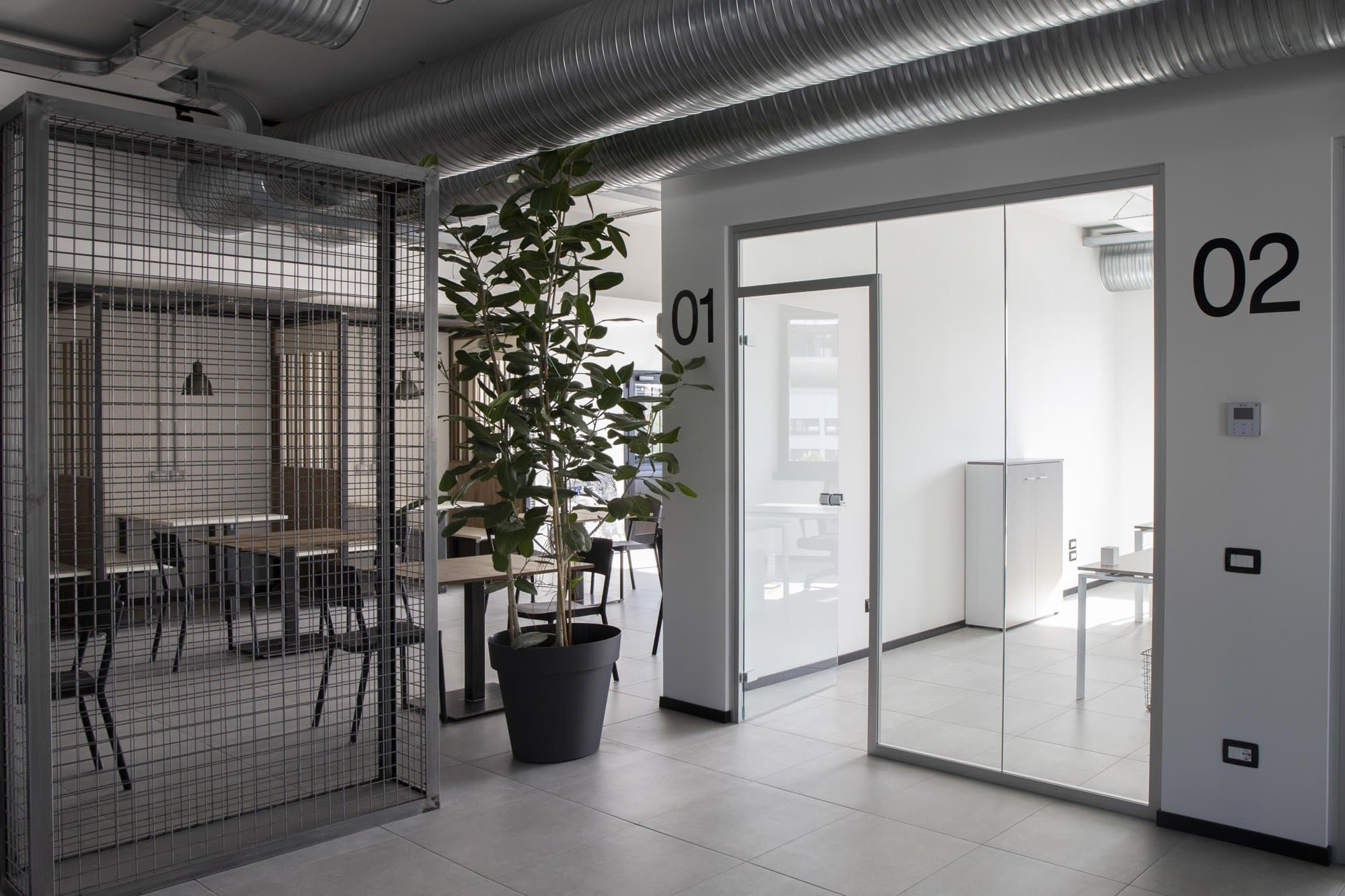 Common area with plants and glass-walled private offices. Common area with plants and glass-walled private offices.